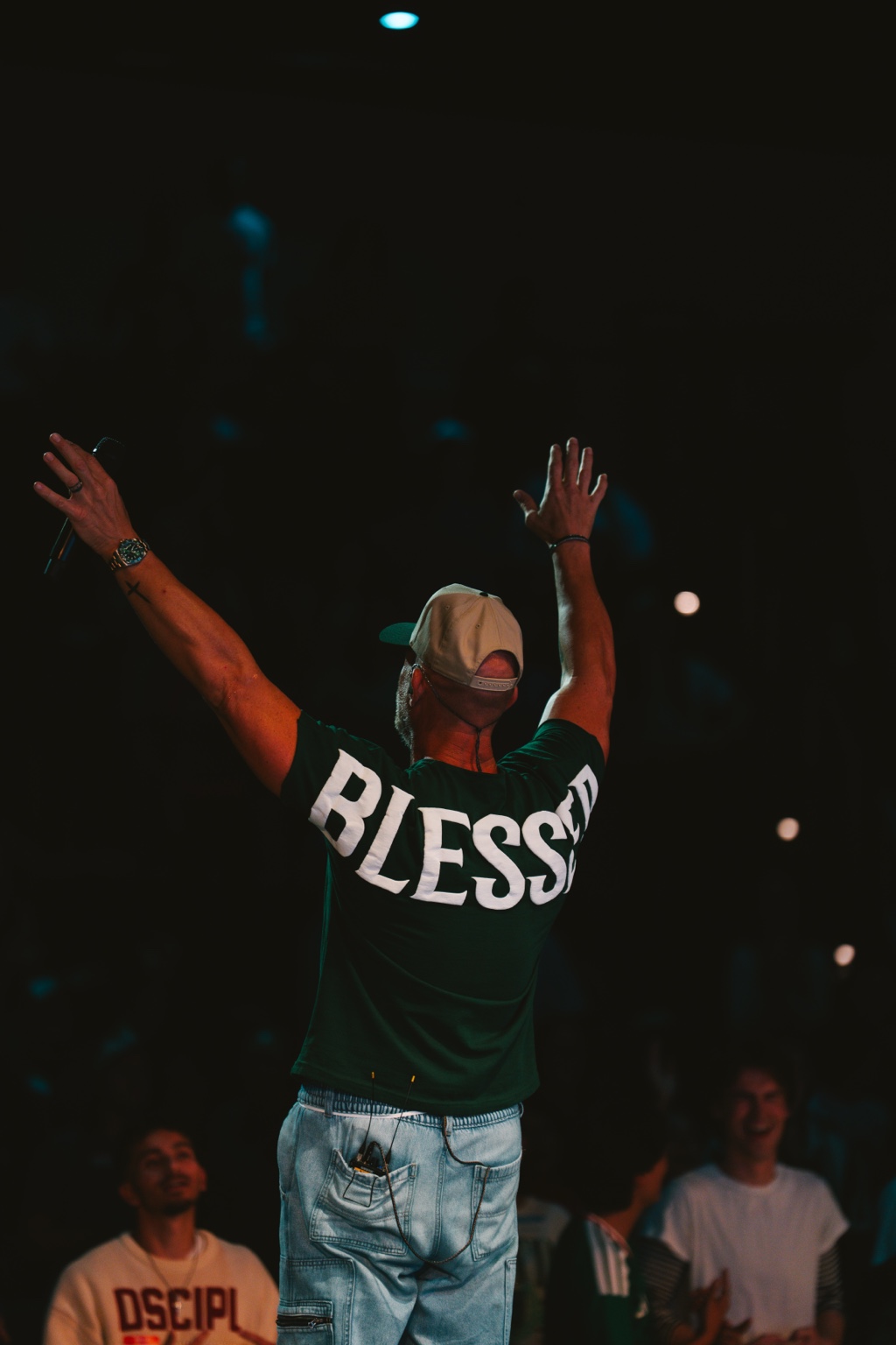 Justin Howard seen from behind, raising both arms during worship
