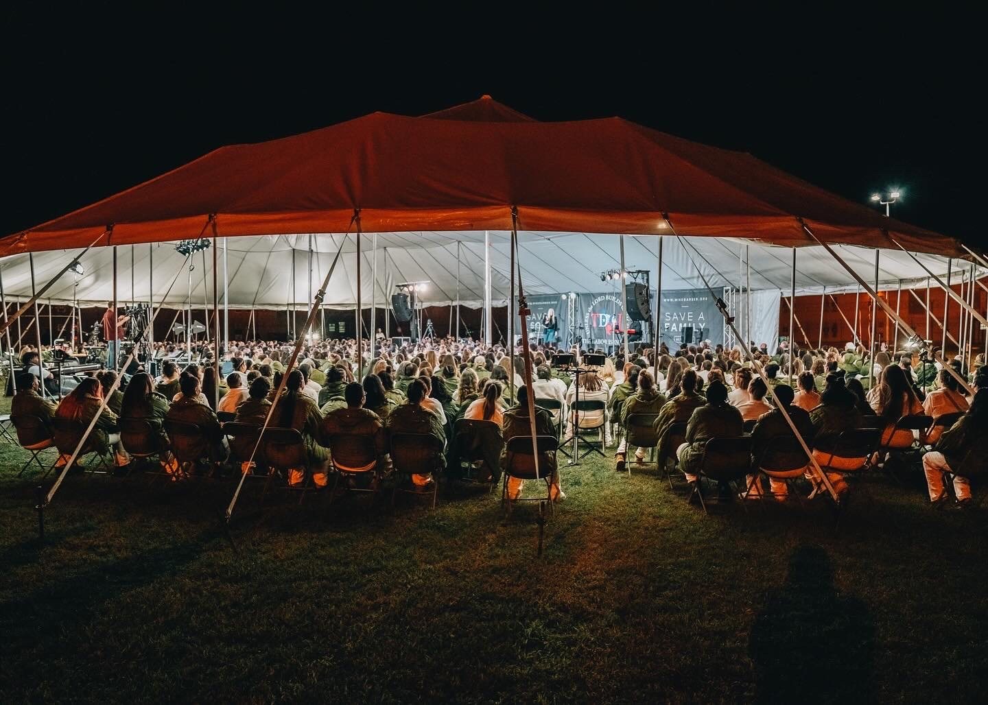 An outdoor evening gathering under a large tent