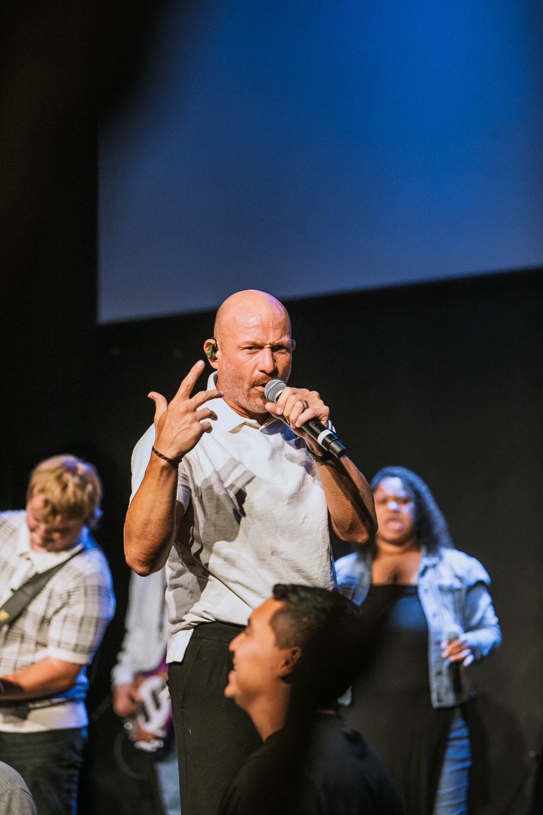 Justin speaking and leading worship with a team on stage