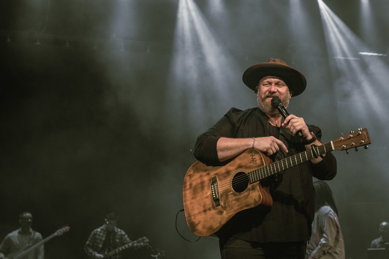 Justin performing on stage with an acoustic guitar